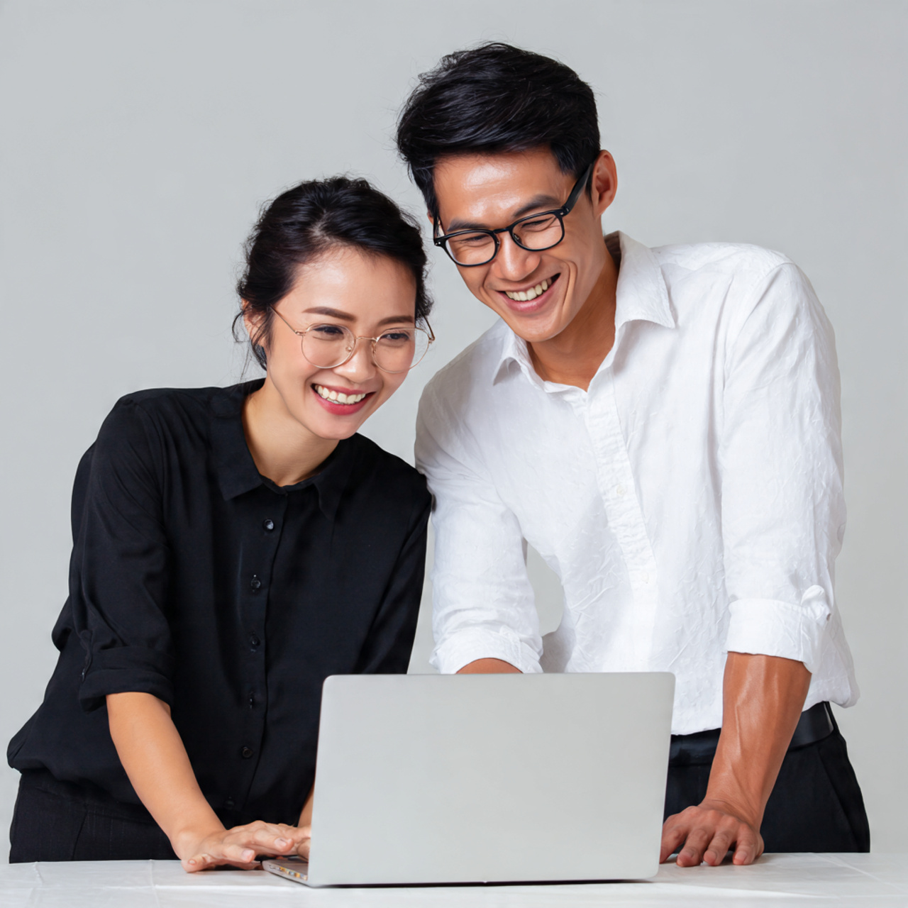 Two people smiling and working together at a laptop